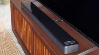 Bose Smart Ultra Soundbar in front of a TV on a wooden surface